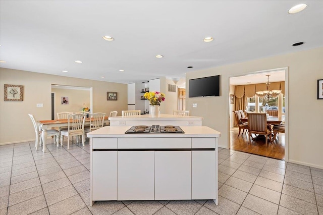 kitchen with white cabinetry, a center island, light tile patterned floors, and black stovetop