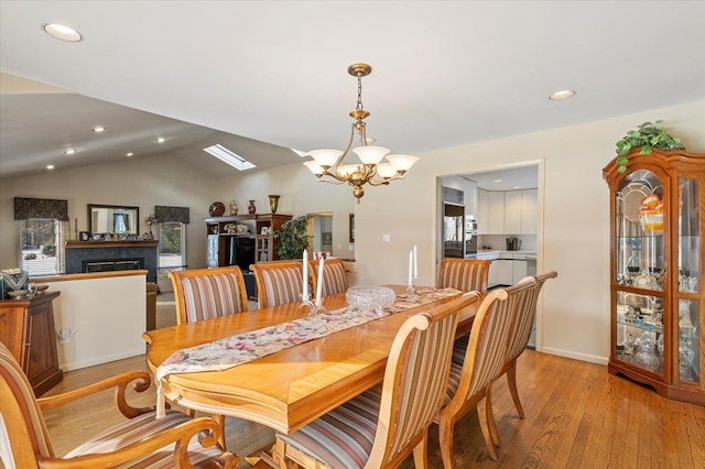 dining room with a notable chandelier, lofted ceiling, and light wood-type flooring