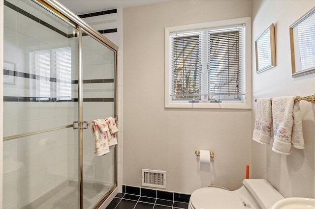 bathroom featuring a shower with door, tile patterned floors, and toilet