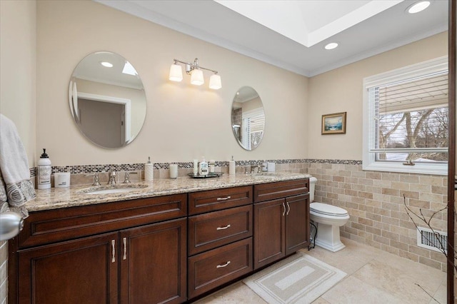 bathroom with tile walls, ornamental molding, vanity, toilet, and tile patterned floors