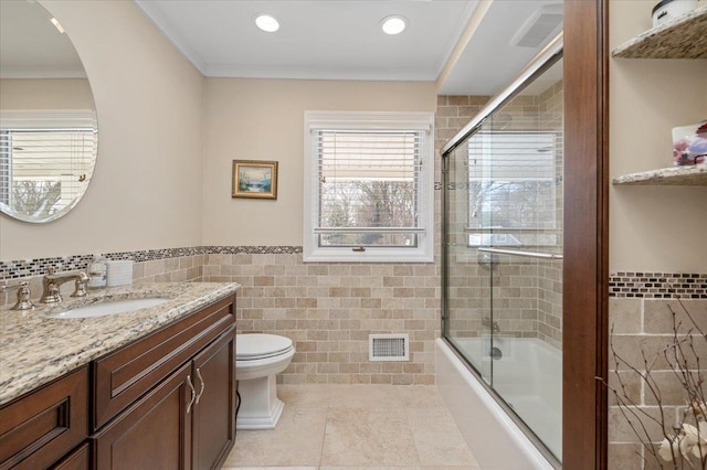 full bathroom with bath / shower combo with glass door, ornamental molding, toilet, and tile walls