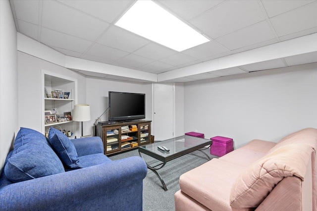 living room featuring built in features and a drop ceiling