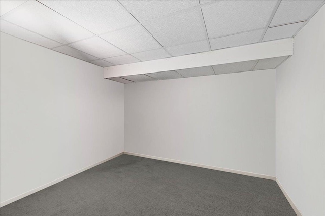 basement featuring a paneled ceiling and dark carpet