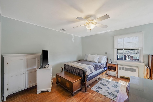 bedroom with hardwood / wood-style floors, radiator heating unit, and ceiling fan