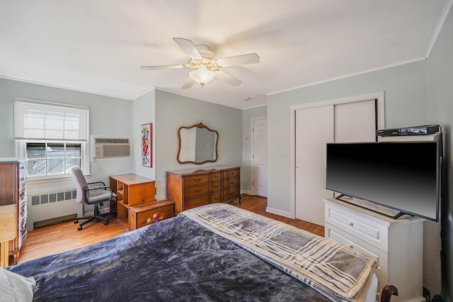 bedroom with radiator heating unit, ceiling fan, light hardwood / wood-style floors, crown molding, and a wall unit AC