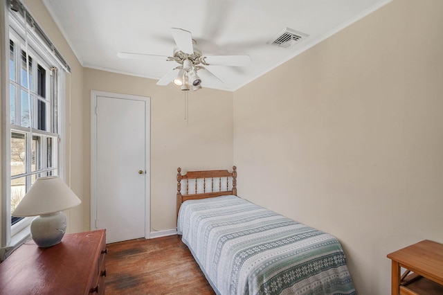 bedroom featuring dark wood-type flooring, ornamental molding, and ceiling fan