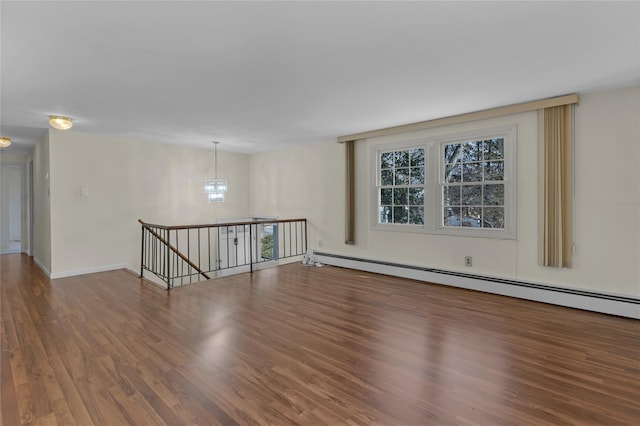 unfurnished room with hardwood / wood-style floors, a notable chandelier, and a baseboard radiator