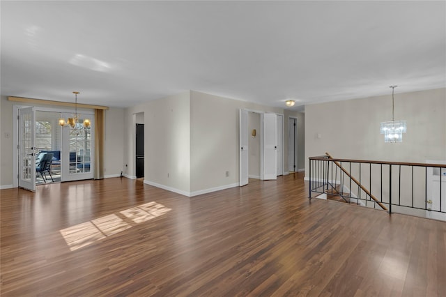 unfurnished room with a notable chandelier and dark wood-type flooring