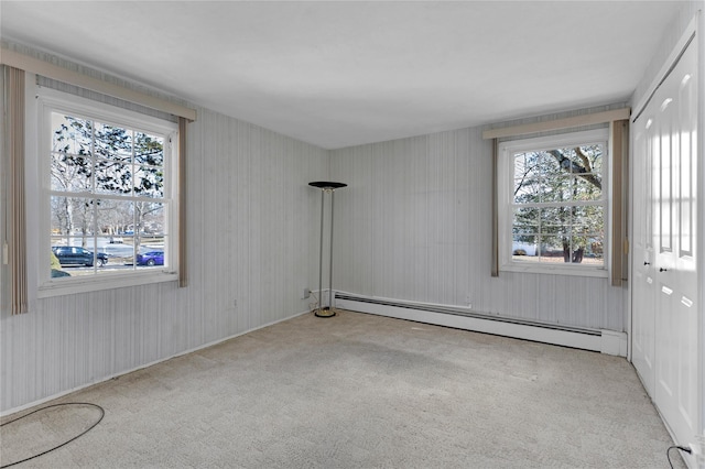 spare room featuring light carpet and a baseboard heating unit