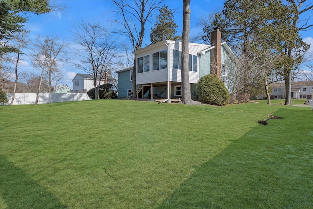 back of house featuring a sunroom and a lawn