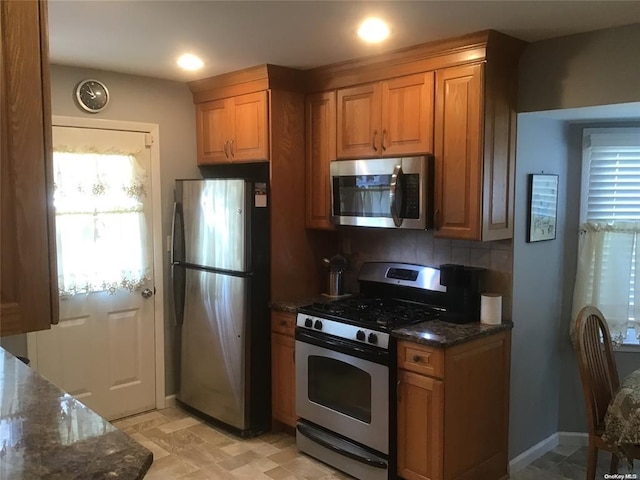 kitchen with dark stone counters, appliances with stainless steel finishes, and tasteful backsplash