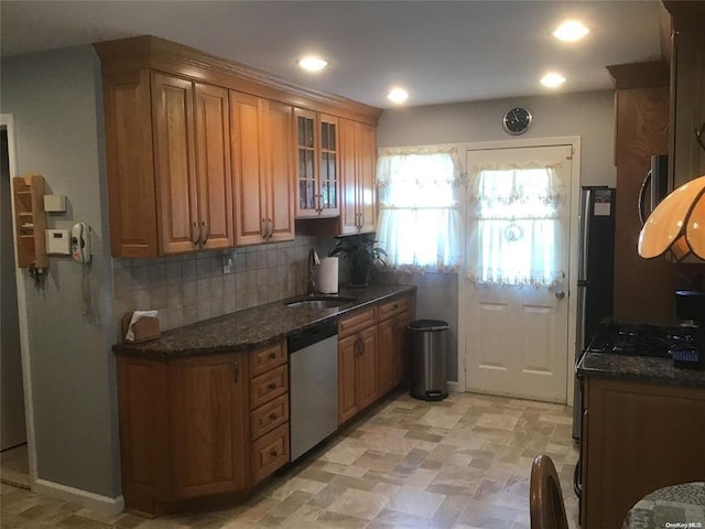 kitchen featuring dishwasher, sink, dark stone counters, black gas stovetop, and decorative backsplash