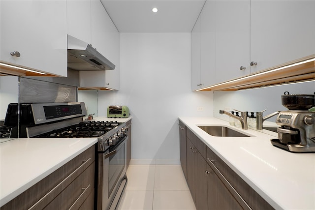 kitchen featuring white cabinetry, light tile patterned floors, dark brown cabinets, sink, and stainless steel range with gas stovetop