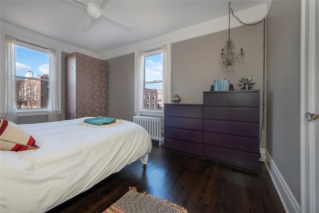 bedroom with ceiling fan with notable chandelier, radiator, and dark hardwood / wood-style flooring