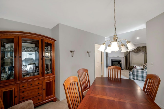 dining space with an inviting chandelier, light carpet, and a tiled fireplace