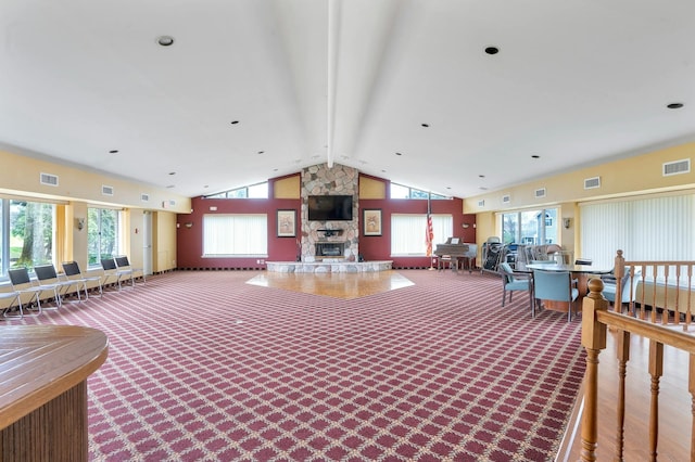 interior space with a stone fireplace and vaulted ceiling with beams