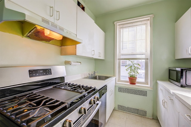 kitchen with light tile patterned flooring, sink, white cabinetry, appliances with stainless steel finishes, and radiator heating unit