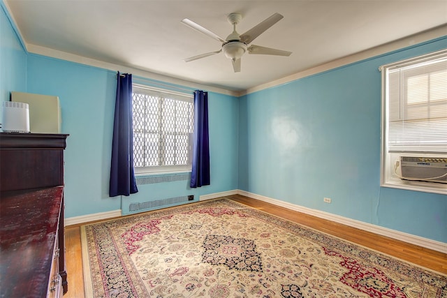 spare room with hardwood / wood-style floors, radiator heating unit, cooling unit, and ceiling fan