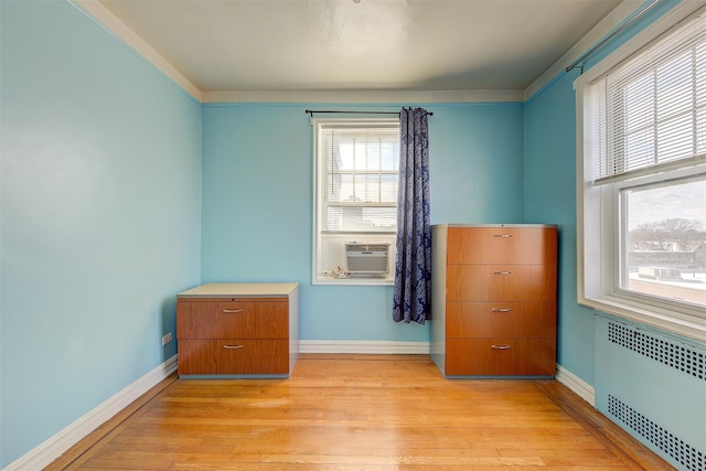 unfurnished bedroom featuring cooling unit, radiator, and light wood-type flooring