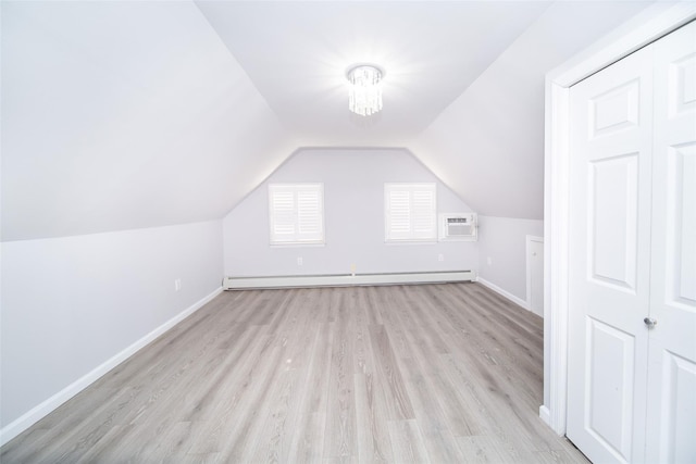 additional living space featuring an AC wall unit, lofted ceiling, baseboard heating, light hardwood / wood-style floors, and an inviting chandelier