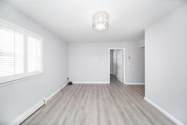 spare room with baseboard heating and light hardwood / wood-style floors