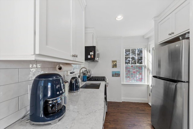 kitchen featuring dark wood-type flooring, white cabinetry, light stone countertops, ornamental molding, and stainless steel appliances