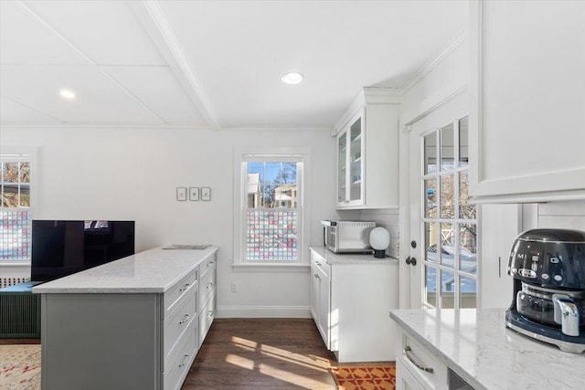 kitchen with light stone countertops, white cabinetry, dark hardwood / wood-style flooring, and ornamental molding