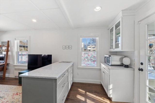 kitchen with dark wood-type flooring, white cabinetry, radiator, and light stone countertops