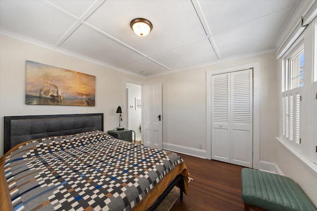 bedroom with a closet, coffered ceiling, ornamental molding, and dark wood-type flooring