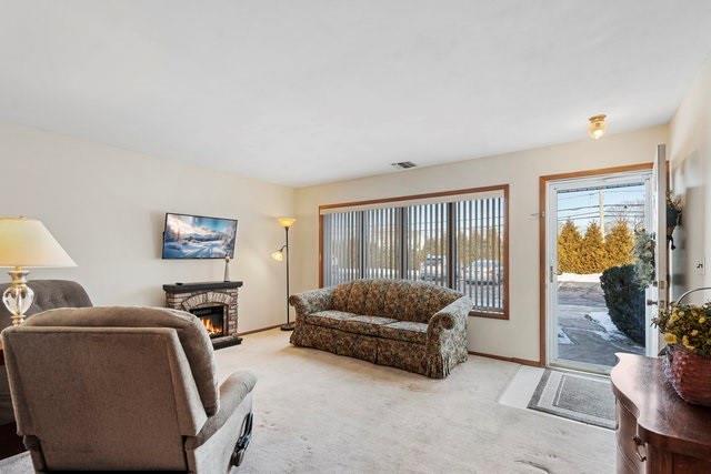 living room featuring light colored carpet and a stone fireplace