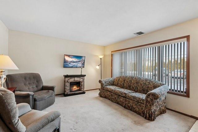 living room with light carpet and a stone fireplace