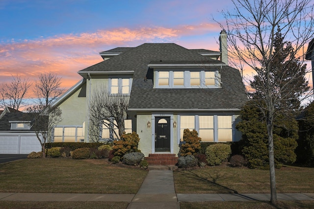 view of front of home with a garage and a lawn