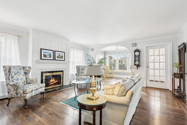 living room with dark hardwood / wood-style flooring, crown molding, and a large fireplace