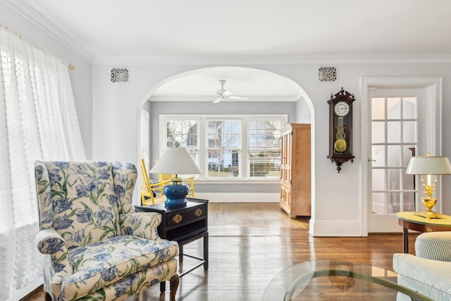 living area featuring hardwood / wood-style flooring, ornamental molding, and ceiling fan