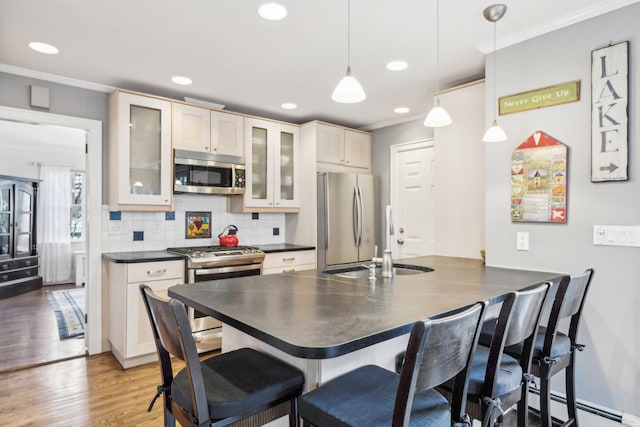 kitchen featuring pendant lighting, sink, crown molding, a breakfast bar, and appliances with stainless steel finishes