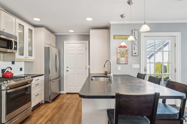 kitchen with sink, crown molding, hardwood / wood-style flooring, pendant lighting, and stainless steel appliances