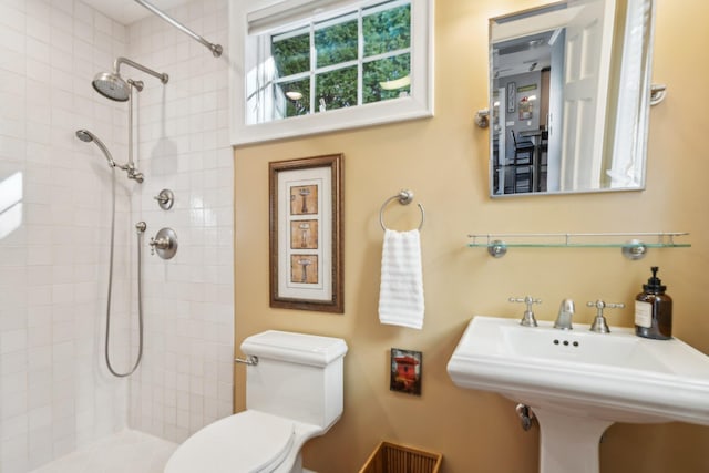 bathroom featuring sink, toilet, and tiled shower