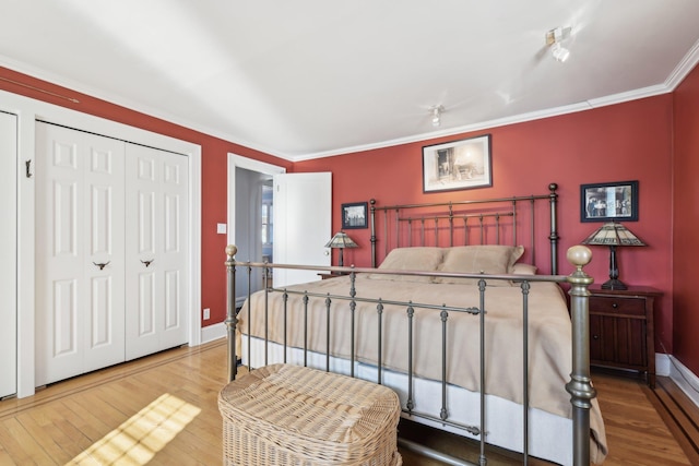 bedroom with wood-type flooring, ornamental molding, and a closet