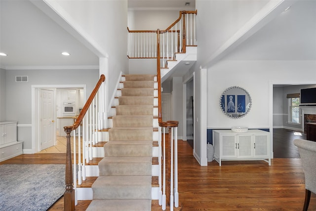 stairway with hardwood / wood-style flooring and ornamental molding