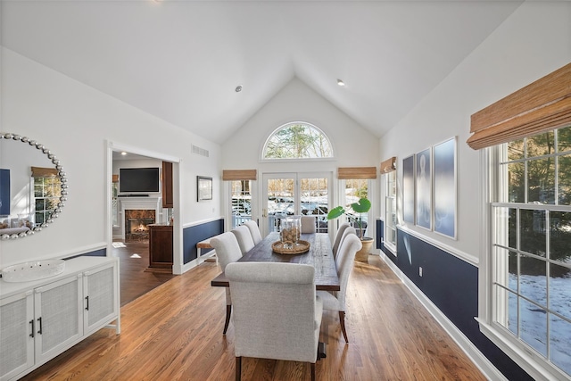 dining area with hardwood / wood-style floors and high vaulted ceiling