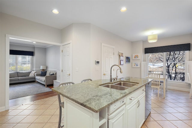 kitchen with light tile patterned flooring, a breakfast bar, sink, and a center island with sink