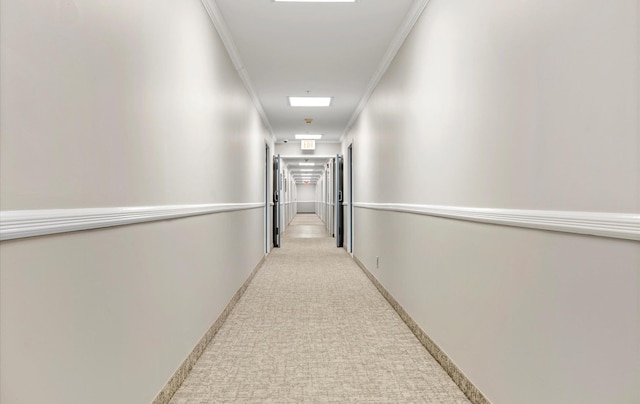 hallway with ornamental molding and light colored carpet