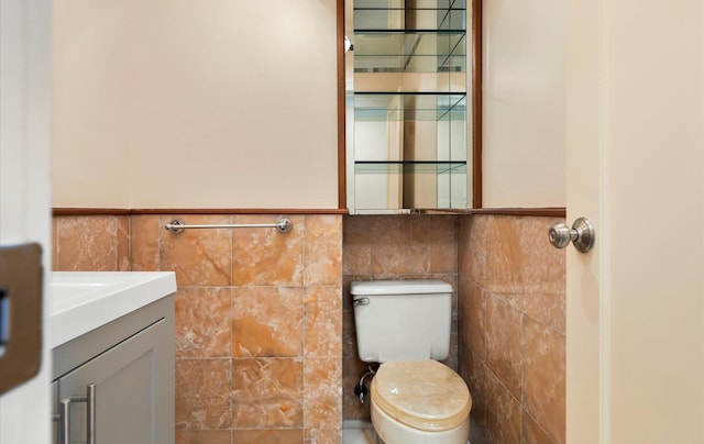 bathroom featuring vanity, toilet, and tile walls