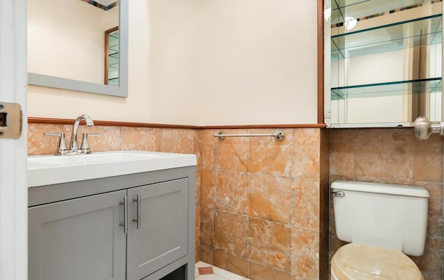 bathroom featuring vanity, tile walls, and toilet