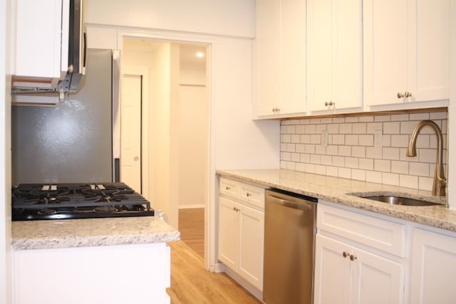 kitchen with stainless steel dishwasher, sink, black gas cooktop, light wood-type flooring, and light stone countertops