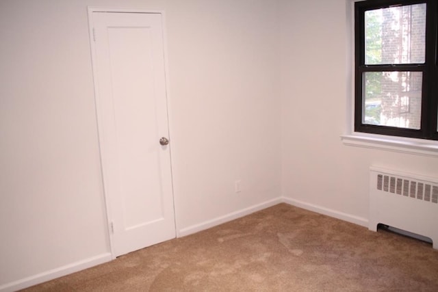 unfurnished bedroom with radiator heating unit and carpet flooring