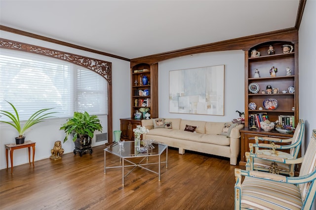 living room with built in features, wood finished floors, visible vents, and crown molding