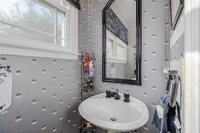 bathroom with a wealth of natural light, a sink, and wallpapered walls