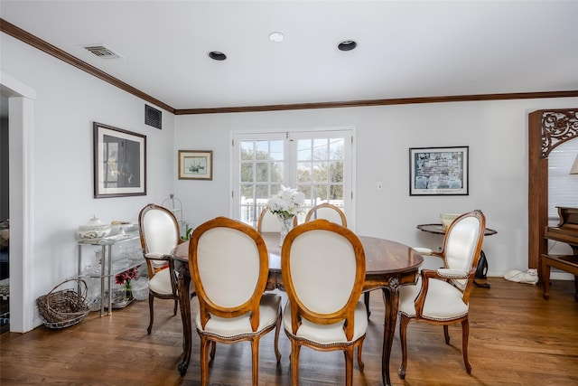 dining room with crown molding, visible vents, and dark wood finished floors