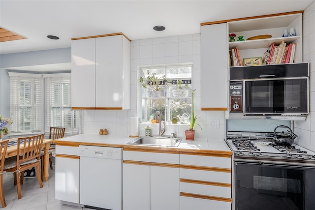 kitchen with white dishwasher, a sink, white cabinetry, and range with gas stovetop